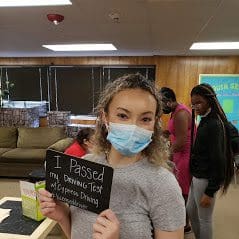 Here's an alt tag for the image: `Student proudly shows off her passed driving test.`